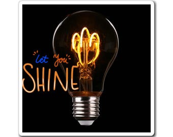 May include: A square sticker featuring a lit Edison light bulb with a glowing filament. The text "Let You SHINE" is written in a cursive font with blue and orange colors against a black background.