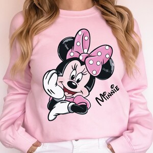 a woman wearing a pink minnie mouse sweatshirt