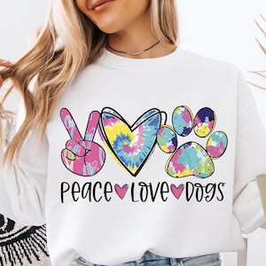 May include: White sweatshirt with a tie-dye peace sign, heart, and paw print design. The text "Peace Love Dogs" is printed below the design.