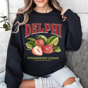 a woman sitting on a couch wearing a black sweatshirt