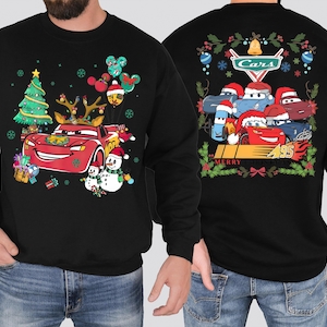 a man wearing a black sweatshirt with cars on it