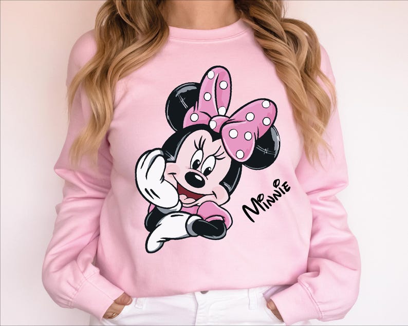 a woman wearing a pink minnie mouse sweatshirt