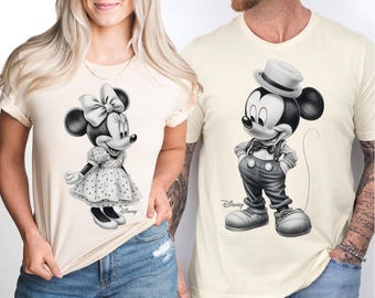 Könnte beinhalten: Ein Paar passende T-Shirts für ein Paar, mit Schwarzweiß-Illustrationen von Mickey und Minnie Mouse. Das Shirt der Frau zeigt Minnie Mouse in einem gepunkteten Kleid mit einer roten Schleife. Das Shirt des Mannes zeigt Mickey Mouse mit Hut und Hosenträgern. Beide Shirts haben den Schriftzug "Disney" aufgedruckt.