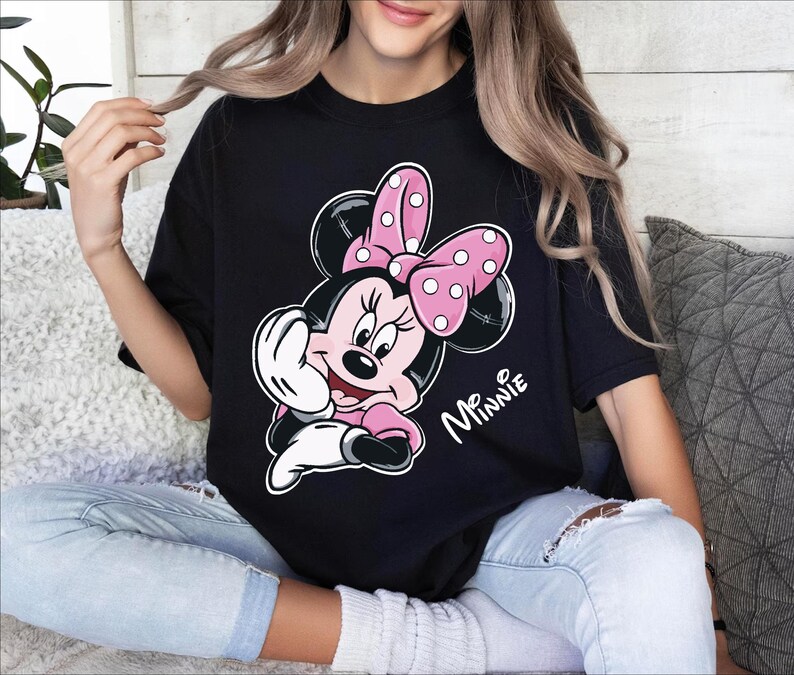 a woman sitting on a couch wearing a minnie mouse t - shirt