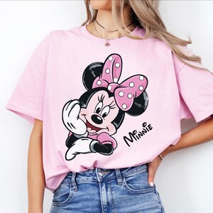 a woman wearing a pink minnie mouse t - shirt