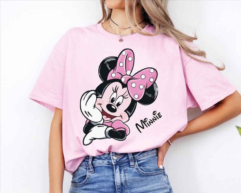 a woman wearing a pink minnie mouse t - shirt