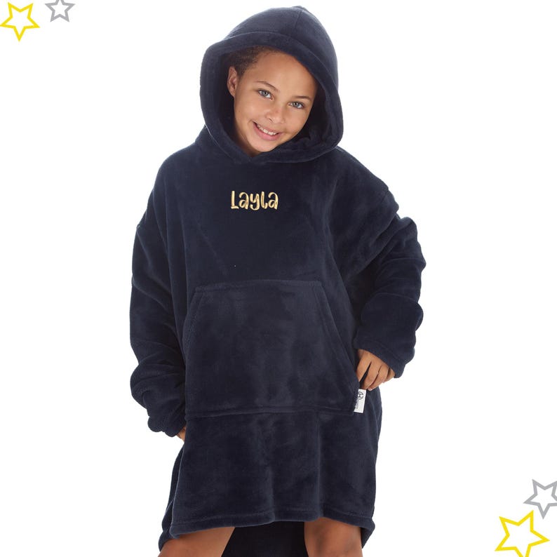 May include: A navy blue oversized hoodie with a hood and a large front pocket. The name "Layla" is embroidered in gold thread on the chest. The hoodie is made of a soft, plush material, perfect for lounging.