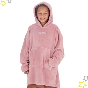 May include: A dusty rose oversized hoodie with a large front pocket and hood. The name "Isabella" is embroidered in silver thread on the chest. The soft, plush material is designed for comfort and warmth. The hoodie is worn by a person.