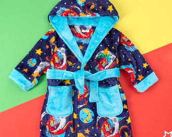 May include: A blue hooded robe with a dragon and stars print. The robe has a blue tie belt and two pockets.