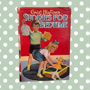 May include: A red hardcover book with the title "Enid Blyton's Stories for Bedtime" on the front cover. The cover features an illustration of two children playing with a doll in a basket.