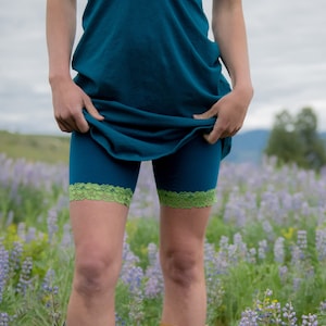 May include: Teal blue shorts with green lace trim. The shorts are made of a soft, stretchy fabric and are perfect for a variety of activities.
