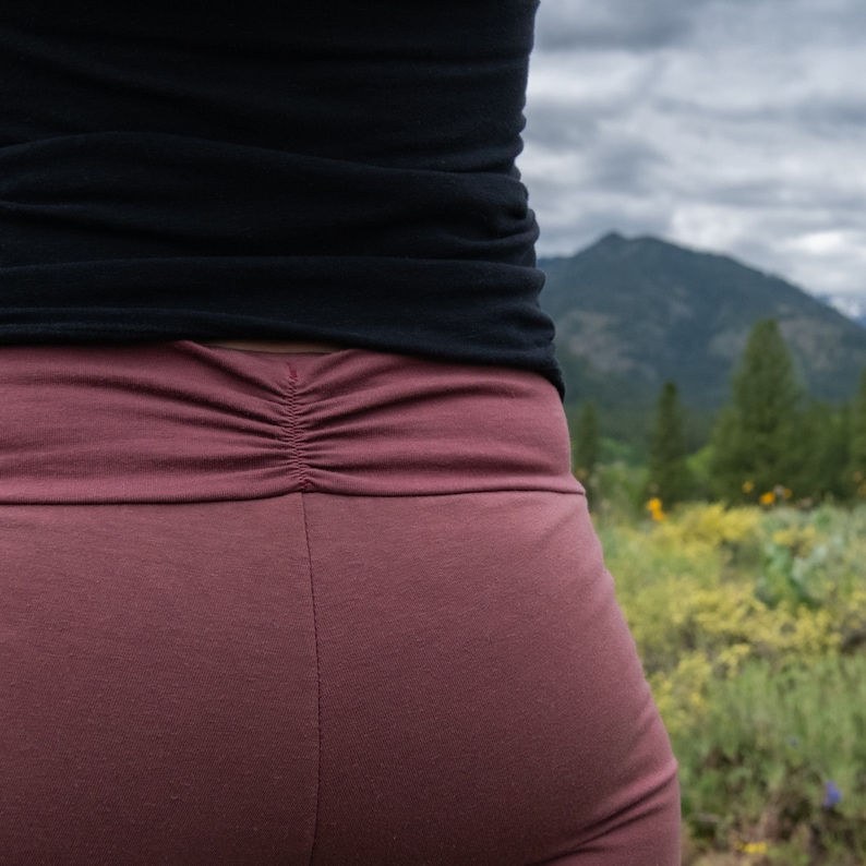 May include: A pair of mauve yoga pants with a gathered back waistband.
