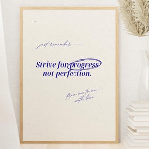 Puede incluir: Un cartel enmarcado con las palabras "Strive for progress not perfection." en escritura azul. El cartel tiene un fondo beige claro y un marco de madera. También se incluye el texto "just remember" y "from me to me - with love".