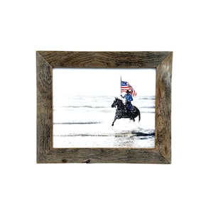 May include: A framed print featuring a person riding a black horse through water, holding a large American flag. The frame is made of rustic, weathered wood. The image is set against a white background.