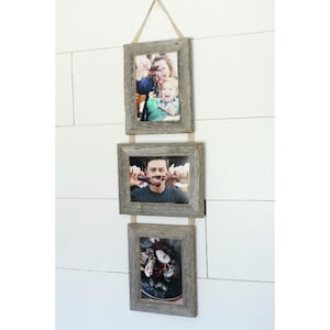 May include: Three rustic wood picture frames with a rope hanger, each displaying a different photo. The frames are arranged vertically, with the top frame showing a woman and a child, the middle frame showing a man, and the bottom frame showing a plate of food.