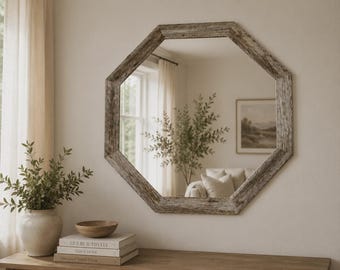 May include: An octagonal wall mirror featuring a weathered, textured gray wooden frame. The mirror reflects a room interior with a window, curtains, a potted plant, and a framed landscape print, showcasing a clear glass surface and a geometric shape.