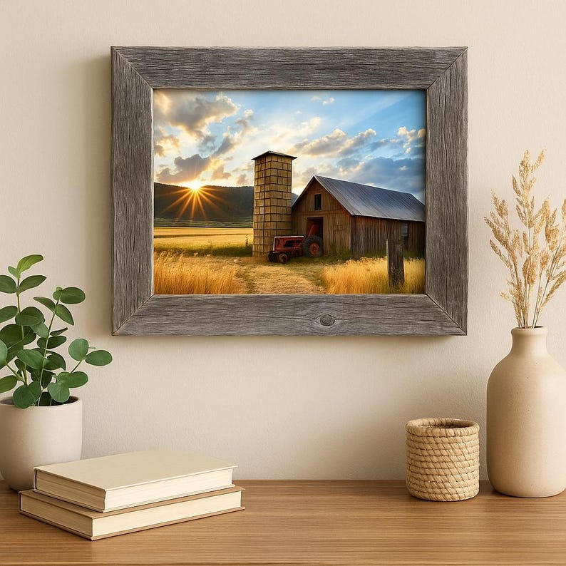 May include: A framed print of a rural landscape featuring a barn, silo, and a red tractor. The artwork depicts a sunset over a field of wheat. The frame is made of weathered gray wood. The overall theme is rustic and pastoral.