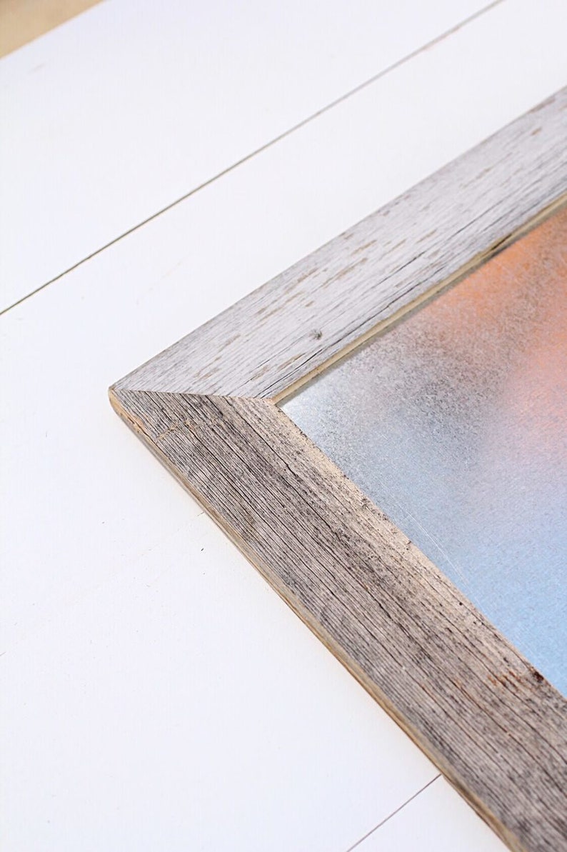 May include: A rustic wooden frame with a light gray, textured, metal insert. The frame has a distressed, whitewashed finish.