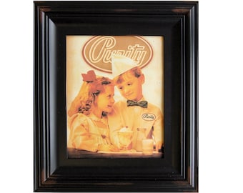 May include: A framed vintage advertisement for Purity ice cream featuring a young boy and girl in a retro setting. The boy is wearing a white hat and a bow tie, while the girl has a red bow in her hair. The ad features the text "Purity" in a stylized font.