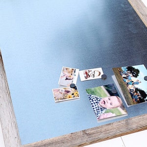 May include: A rustic wooden framed magnetic board with a light blue metal surface.  Four photos are attached to the board with magnets.