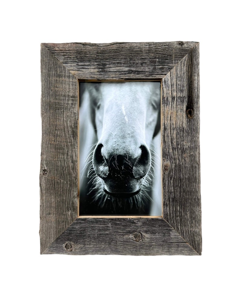 May include: A rustic, rectangular picture frame with a black and white photograph of a horse's nose. The frame is made of weathered, gray wood with visible knots and a rough texture, adding a natural, vintage aesthetic.
