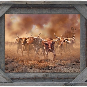 May include: A framed print depicting a herd of longhorn cattle running through a dusty landscape. The image features a sepia-toned color palette with a windmill in the background. The frame is made of weathered gray wood with barbed wire accents.