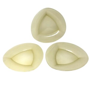 May include: Three off-white, triangular-shaped dishes. Each dish has a rounded, egg-like shape with a triangular interior. The dishes are arranged on a white background, showcasing their unique design and color.