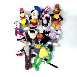 Puede incluir: Una colección de peluches con personajes de dibujos animados populares. Los peluches están hechos de tela suave y colorida e incluyen una variedad de personajes, como un gallo, una rana, un gato y un perro. Los peluches están todos en buen estado y serían una gran adición a la colección de juguetes de cualquier niño.