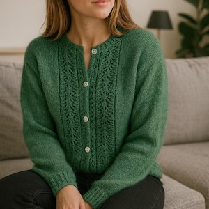 Puede incluir: Un cárdigan verde con cuello redondo y cierre de botones. El suéter presenta un diseño texturizado de punto calado en la parte delantera. La modelo lleva vaqueros negros. El cárdigan está hecho de un material de punto suave.