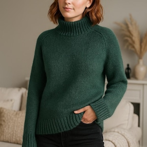 May include: A dark green turtleneck jumper with long sleeves. The jumper is made of a soft, textured knit fabric. The model is wearing black jeans. The background includes a sofa and decorative items.
