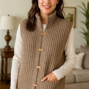 “Front view of sleeveless knitted vest showing button band and ribbed edges.”
