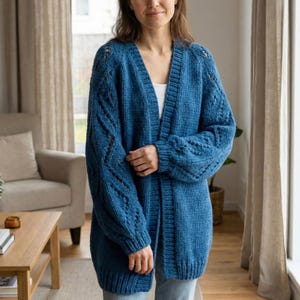 Puede incluir: Un cárdigan largo y abierto en un vibrante tono azul. El suéter de punto presenta un cuello en V, intrincados detalles de punto de cable en las mangas y un ajuste relajado. El cárdigan está hecho de un material de punto grueso y suave.