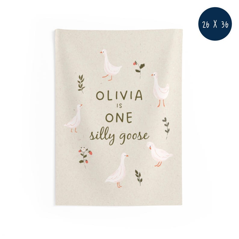 May include: A beige wall hanging with the text "Olivia is One silly goose" and illustrations of white geese, leaves, and flowers. The wall hanging measures 26 x 36 inches.