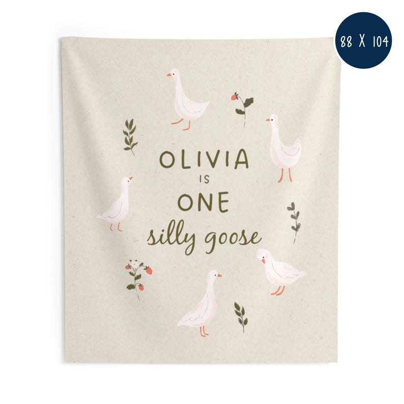 May include: A beige tapestry with the text "OLIVIA IS ONE silly goose" surrounded by illustrations of white geese, sprigs, and berries. The tapestry measures 88 x 104 inches.