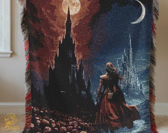 Op de afbeelding: Geweven sprei met een fantasielandschap met een vrouw in een rode jurk, twee kastelen, een volle maan en een halve maan. De deken heeft een rood, zwart en wit gefranjerde rand. Het kunstwerk is in tinten rood, zwart en blauw.