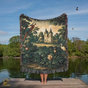 Könnte beinhalten: Gewebte Wandteppich-Wurfdecke mit einer detaillierten Landschaftsszene mit einem Schloss, einem Papagei und Blumen. Der Überwurf hat einen Fransenrand. Die Farbpalette umfasst Grün-, Braun- und Cremetöne. Der Hintergrund ist ein blauer Himmel und Wasser.