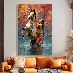Puede incluir: Un gran lienzo representa a una mujer con largas trenzas oscuras interactuando con un caballo encabritado en el agua. El caballo es blanco y marrón. El fondo presenta follaje otoñal en tonos rojos, naranjas y amarillos.