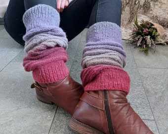 May include: A person wearing dark jeans and brown leather boots with a zipper. The boots are paired with knitted leg warmers in shades of purple, pink, and gray. The leg warmers are ribbed and scrunched down over the boots.