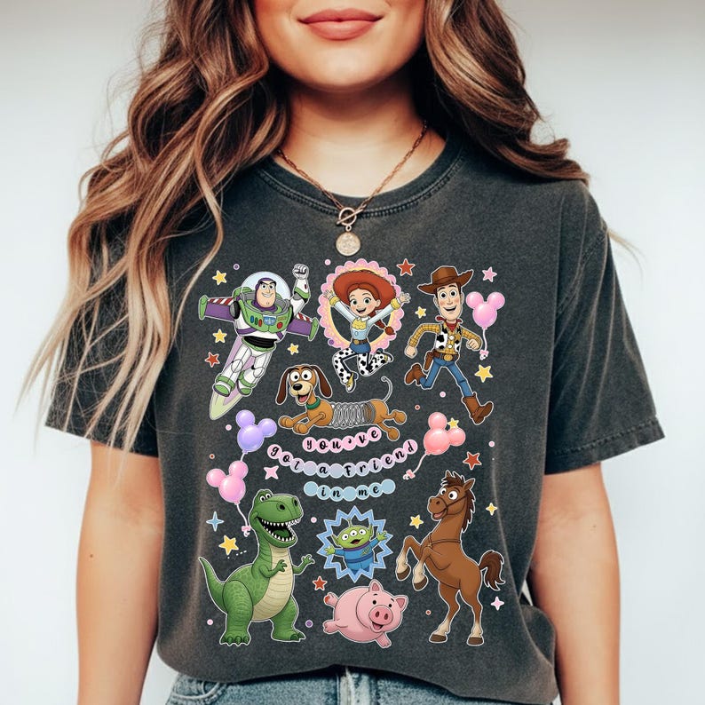 May include: Dark gray t-shirt featuring colorful cartoon characters from a popular animated movie. The design includes Buzz Lightyear, Woody, Jessie, and other characters, along with the text "Get a friend in me."
