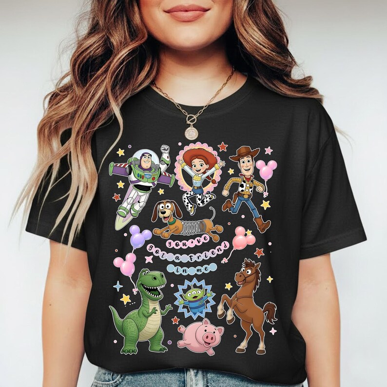 May include: Black t-shirt featuring colorful cartoon characters from the Toy Story movie. The design includes Buzz Lightyear, Woody, Jessie, Rex, Slinky Dog, and other characters. The text "You've Got a Friend in Me" is also included.