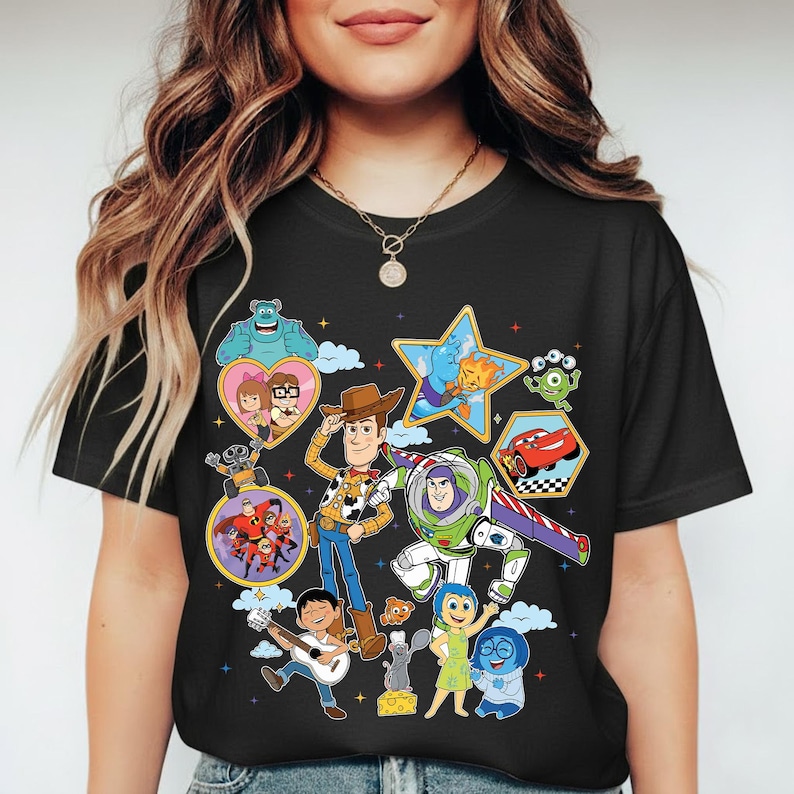 May include: Black t-shirt featuring a colorful collage of animated characters. The design includes Woody, Buzz Lightyear, Mike Wazowski, and other characters from popular animated movies. The shirt is a crew neck style.