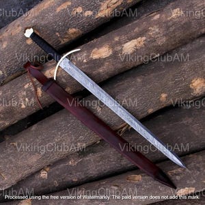 Peut inclure: Une épée à double tranchant avec une lame en acier Damas à motifs, une poignée gainée de cuir noir, un pommeau argenté et une garde incurvée. L'épée est accompagnée d'un fourreau en cuir marron foncé avec un cordon en cuir assorti.