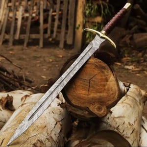 Peut inclure: Une épée ornée avec une lame à motifs et un manche en cuir marron. La garde et le pommeau sont dorés. L'épée est posée sur une bûche, suggérant un thème rustique ou historique.