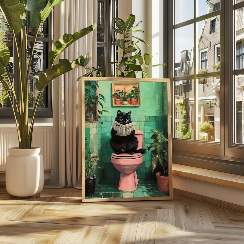 May include: A black cat sitting on a pink toilet in a bathroom with green tile walls and a newspaper in its paws. The cat is looking at the newspaper. There are plants in the bathroom.