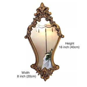 May include: A gold ornate mirror with a decorative frame. The mirror is 16 inches tall and 8 inches wide.