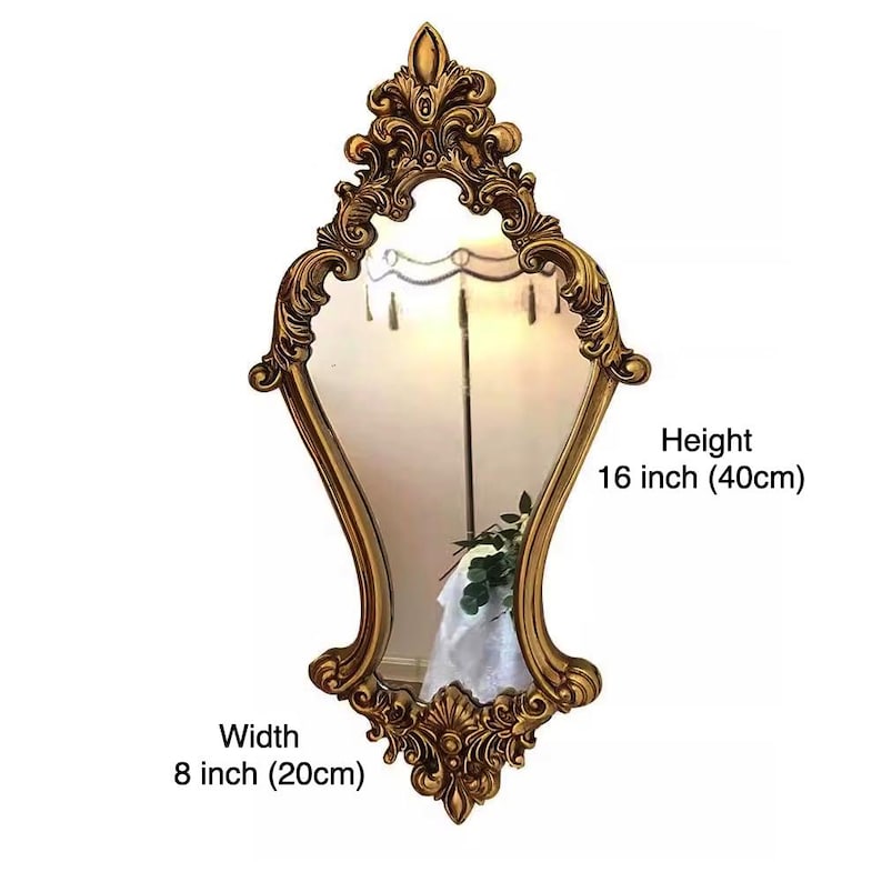 May include: A gold ornate mirror with a decorative frame. The mirror is 16 inches tall and 8 inches wide.