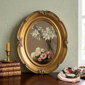 Arte floral vintage enmarcado con rosas y lirios: marco ovalado dorado ornamentado, decoración romántica para pared.