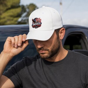 May include: White baseball cap with a curved brim. The cap features a graphic of an eagle, American flag, and the text "MAKE AMERICA GREAT AGAIN" in red, white, and blue. The cap is being held by a person.