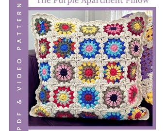 May include: A square, multi-colored crochet pillow with a floral pattern. The pillow features a cream-colored border and is filled with colorful squares in shades of blue, pink, yellow, and green. Text on the image reads "The Purple Apartment Pillow" and "PDF & VIDEO PATTERN".