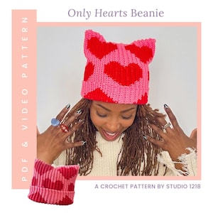 May include: A pink and red crochet beanie with heart patterns and cat ears. The text "Only Hearts Beanie" is at the top. The image also includes the text "PDF & VIDEO PATTERN" and "A CROCHET PATTERN BY STUDIO 1218".
